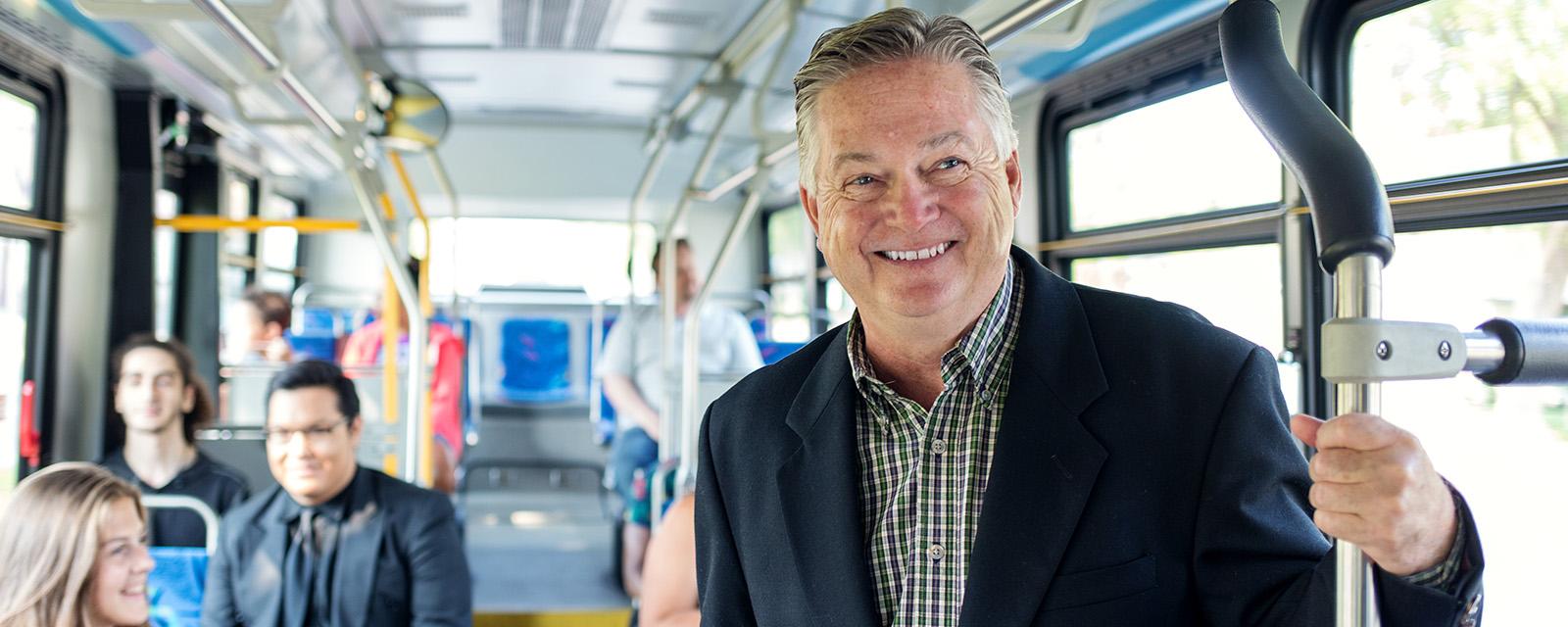 Man standing in bus holding on to rail